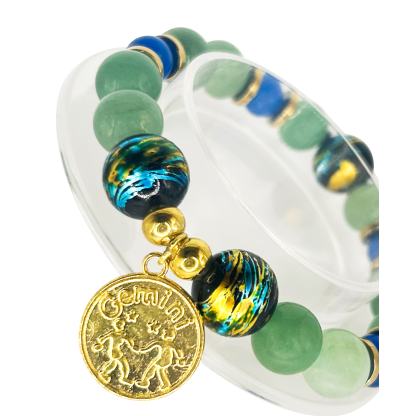 Close-up of green aventurine and dyed blue agate Gemini bracelet featuring gold foil glass beads and a gold Gemini zodiac charm with twin figures and stars.