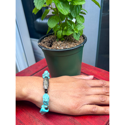 Turquoise Nugget Bracelet on wrist with silver centerpiece, styled outdoors with mint plant and red wooden table
