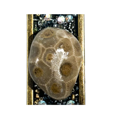 Close-up of Petoskey Stone pendant on a white background, highlighting coral pattern and beaded crystal border.