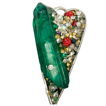 Close-up of heart pendant with emerald crystal and embedded multicolored stones